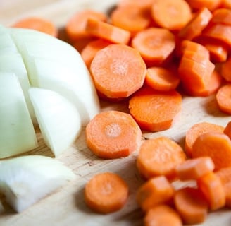 a cutting board with onions and carrots on it