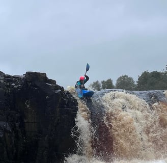 a women paddling a Pyranha Scorch off a waterfall (low force waterfall on the Tees) 
