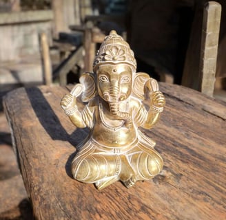 La imagen es una figura decorativa de Ganesha sobre una mesa de madera