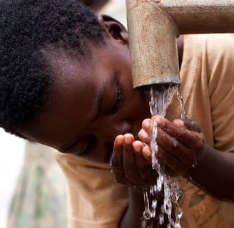African child drinking clean water from a pipe with cupped hands