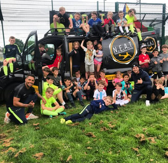 a big group of children by the NEAT fun bus