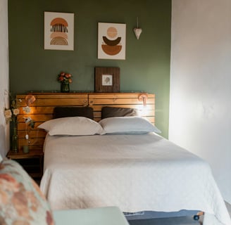 a bedroom with two beds and a wooden headboard green accent wall