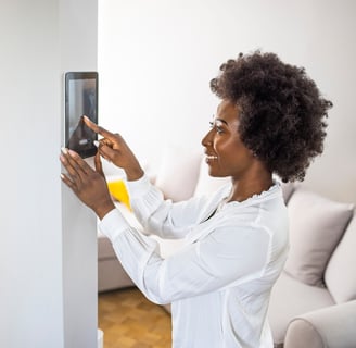 black woman adjusting smart home via tablet on the wall