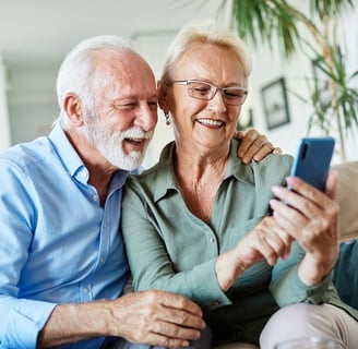 older couple smiling while looking at a smart phone