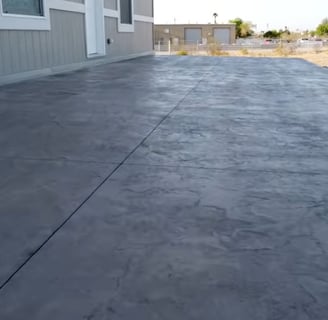 a stamped concrete patio area in the rear of a house colored in grey cement
