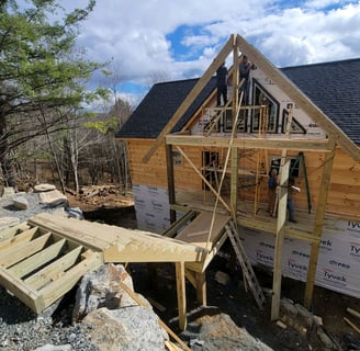 3 construction workers working together to build a staircase to a newly constructed porch for a home
