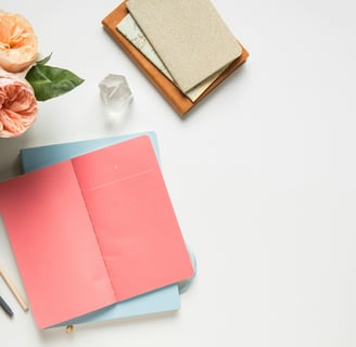 a desk with a notebook and a pen and a flower / un bureau avec un cahier, un stylo et une fleur