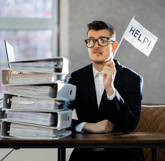 a man in a suit and glasses sitting at a desk with a laptop computer