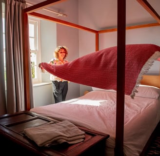 a woman standing in front of a bed with a blanket on it