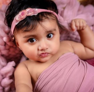 a baby girl in a pink dress and headband