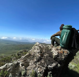 a man sitting on a rock with a backpack on top of it
