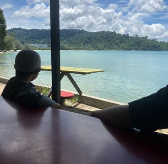 boy sitting at cafe overlooking ocean and mountain