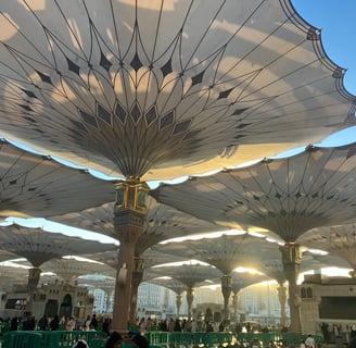 a group of people standing around a large umbrella of Medina, Saudi Arabia