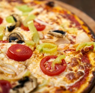 a pizza with tomatoes and mushrooms on a wooden board