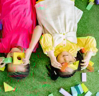 two children playing with blocks on a green carpet