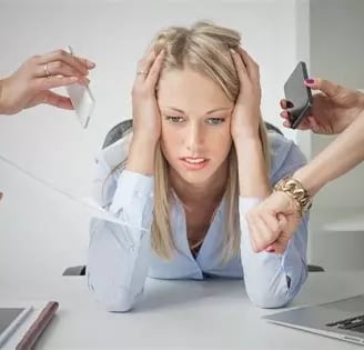 Femme blonde de face stressée se tient la tête à 2 mains et penchée en avant