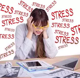 Femme stressée penchée en avant avec lunettes jaunes, se tient la tête mains sur les oreilles