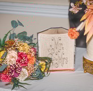 Bouquet of paper roses, Mr & Mrs carved into the pages of a Harry Potter book and wedding cake displayed on table