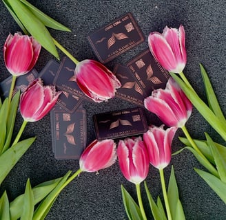 Luxury black business cards for The Divine Touch, styled with pink tulips on a dark background.