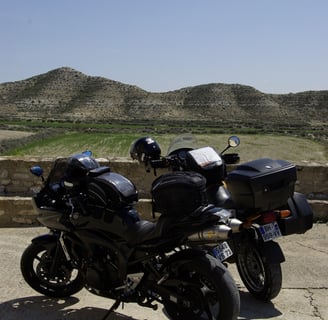 a motorcycle parked on a concrete surface with a mountain in the background