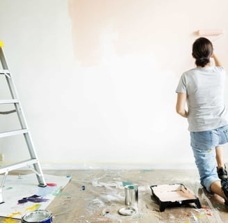 a woman is painting a wall with a ladder withe adom.ma