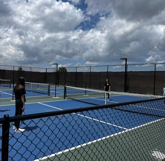 Group of kids playing pickleball on outdoor courts during a Smart Dinker youth session.