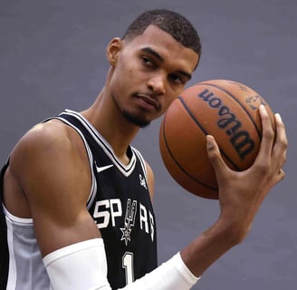 Victor Wembanyama posing with basketball in Spurs jersey
