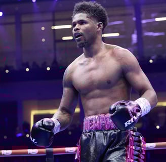 Shakur Stevenson flexing in boxing ring under purple lights