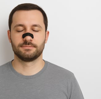 Primer plano de hombre aplicándose la tira nasal RESPIRA+ antes de dormir.