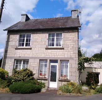 Stone holiday home with a small garden featuring rose bushes and greenery, offering a cosy countrysi