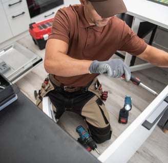 a Handyman in a brown shirt and a tool belt fixing door in New West