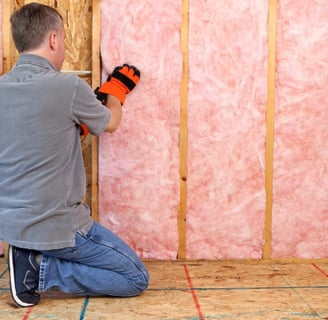 a man in a gray shirt and orange gloves installing insulation in Squamish