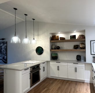 Contemporary kitchen corner with white shaker base cabinets, quartz countertops, wood shelving, and 