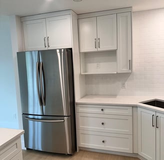 Corner view of a modern kitchen with white shaker cabinets, deep drawers, quartz countertops, and a 