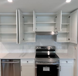 White shaker kitchen cabinets with open doors showing adjustable shelving, subway tile backsplash, q