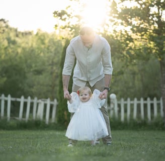 a man and a baby girl walking in the grass