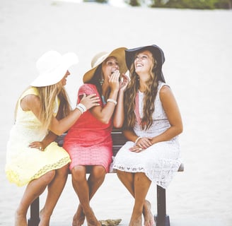 three women sitting on a bench in the sand