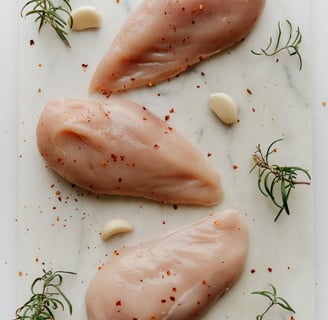 Fresh raw chicken breasts on a wooden cutting board, ready for seasoning and air frying.