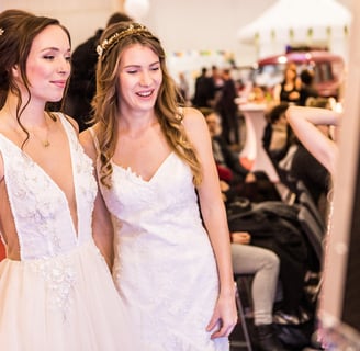 two bridesmaid women in white dresses standing in a room