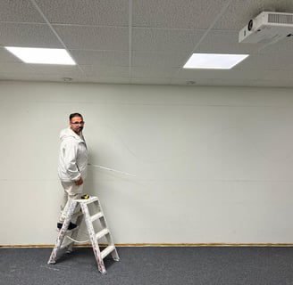 Homme sur un escabeau prenant des mesures.