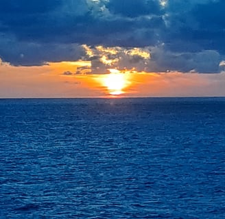 Deep blue ocean with orange sunset and deep blue clouds in sky