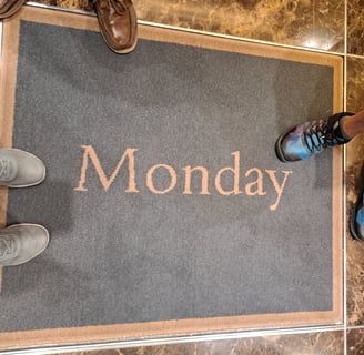 Feet on a rug that says "Monday"