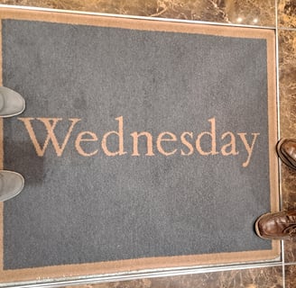 Two pairs of feet around a rug that says "Wednesday"