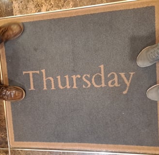 two pairs of shoes around a rug a that says "Thursday"