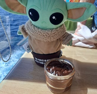 Little Green companion standing in front of cake in a jar