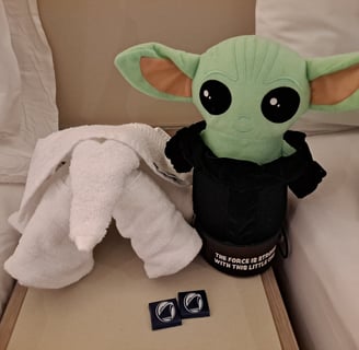 Little green companion and Towel elephant on night stand