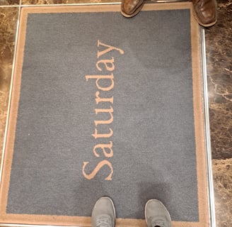 Two pairs of shoes around rug that says "Saturday"