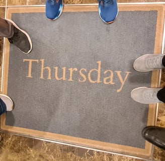 Feet around a rug that says "Thursday"