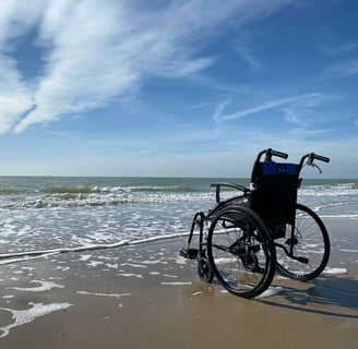 Wheelchair at edge of water on beach. Photo credit - Photo by //unsplash.com/@hansmoe