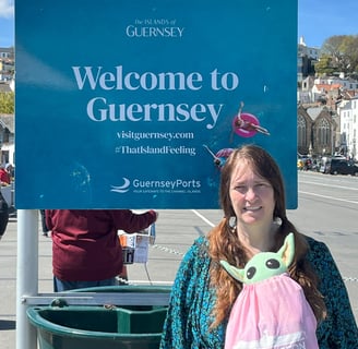 Woman in front of sign that says "Welcome to Guernsey"